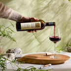 A person pours a bottle of Mount Veeder Reserve Cabernet Sauvignon into a glass on a wooden surface