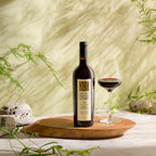 Bottle of Mount Veeder Winery Reserve Cabernet Sauvignon, glass of wine on a wood tray with natural background.