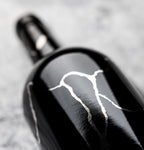 Bottle of Grenache Syrah Mourvedre on its side on gray background