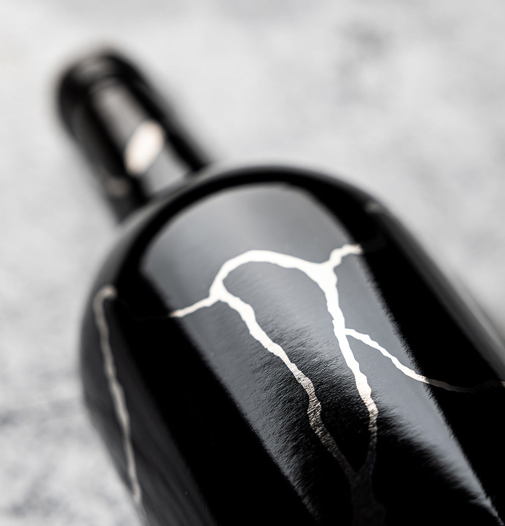 Bottle of Grenache Syrah Mourvedre on its side on gray background