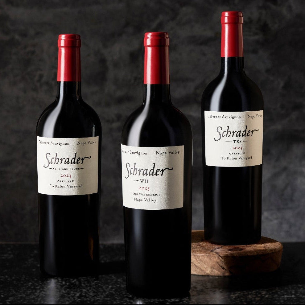 Three bottles of Schrader wine on a dark background