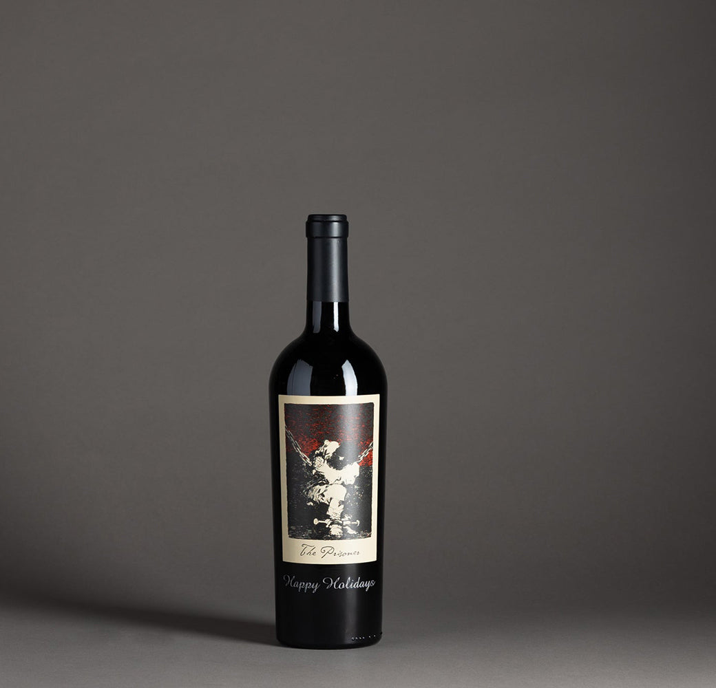 The Prisoner Red Blend etched with "Happy Holidays" in a black gift box on a gray background