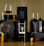 The Prisoner Red Blend Magnum Etched with "Happy Holidays" in a black gift box next to wine glasses