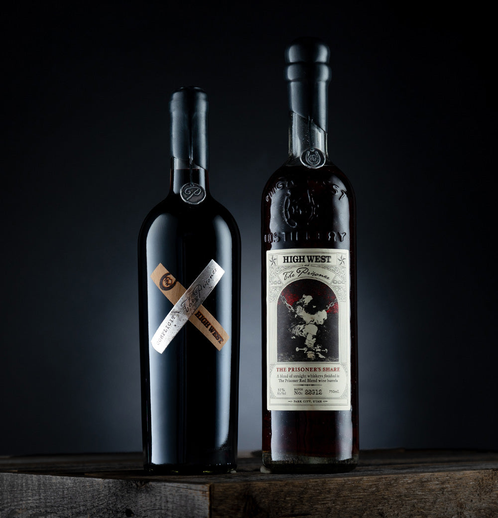 Complicit red wine bottle next to whiskey bottle 
